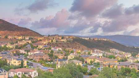 Panorama Puffy clouds at sunset Residential area in between the mountains against the colorful sky...