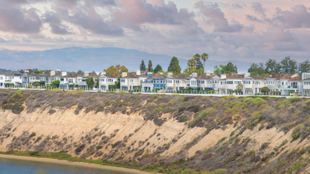 Panorama Puffy clouds at sunset Newport Beach neigborhood near the slope of the waterfront at California. Fenced residential area with trees, waterfront and mountain view background.の写真素材