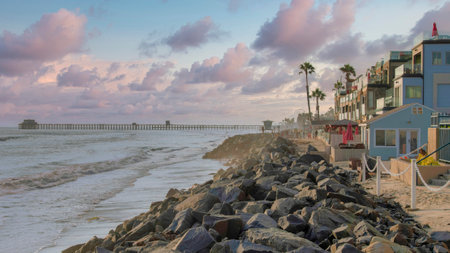 Panorama Puffy clouds at sunset Beach at the coastal area of Oceanside in California with a view of the pier. There is a natural rock seawall in the middle of the buildings on the right and sea on the left.の写真素材