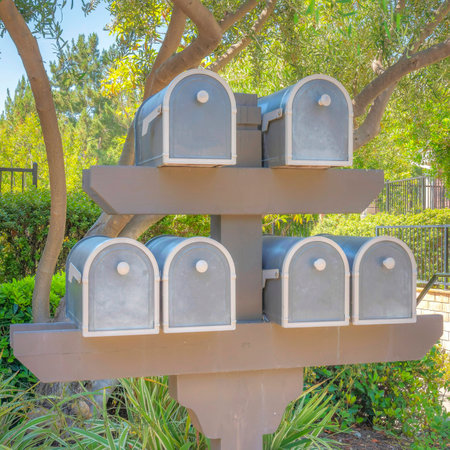 Square Mailboxes rack at Ladera Ranch in Southern California. Mailboxes near the plants and trees outside the fenced residences at the back with handrails on the left.の写真素材