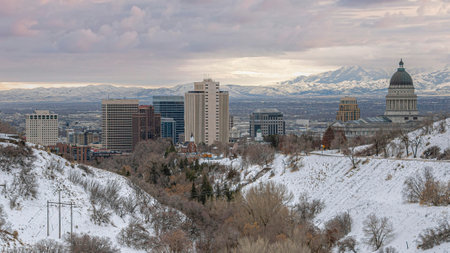 Panorama Puffy clouds at sunset Curved road in the middle of snowy hills at Salt Lake City, Utah. There are large institutional and commercial buildings against the view of mountains and cloudy sky.の写真素材