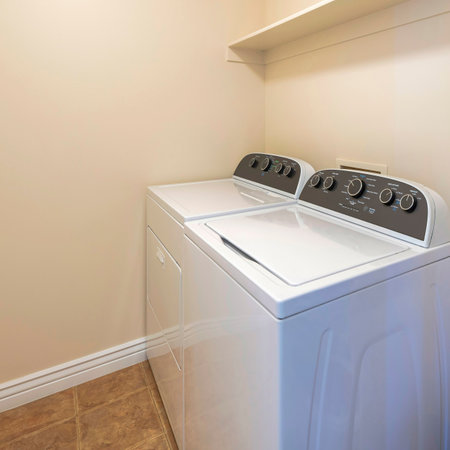 Square Interior of a laundry room with a shelvings with stack of colorful blankets. There are laundry units near the wall with shelves on top with box and detergent soaps.の写真素材