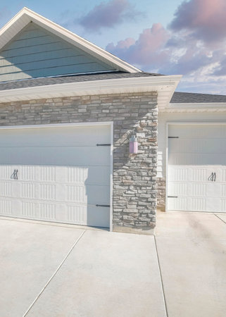 Vertical Puffy clouds at sunset Three-car side hinged garage doors with stone veneer wall siding....