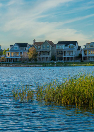 Vertical Whispy white clouds Oquirrh Lake waterfront during sunset at Daybreak, Utah. There is a covered dock on the left and large residential houses against the sky horizon and mountain at the background.の写真素材