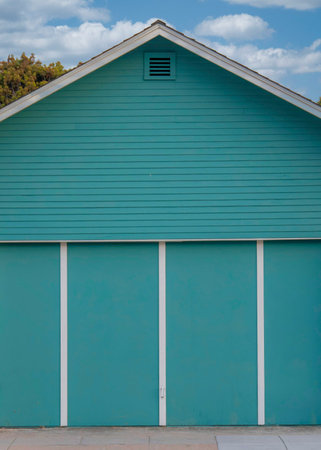 Vertical White puffy clouds Aqua blue detached garage exterior at Oceanside, California. Garage exterior with bi-fold doors against the houses at thee background.の写真素材