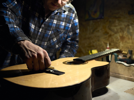 In the guitar workshop, Guitars Luthiers installs a saddle.の写真素材