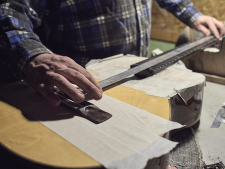 Installation frets on the neck of the guitar. The specialist checks the distance between the frets and the bridge.