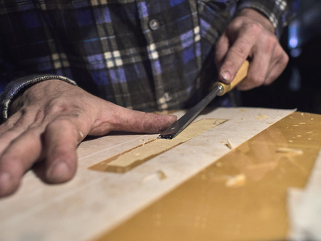 Installing a bridge on classical guitar body. The specialist removes varnish from the body of the guitar.の写真素材