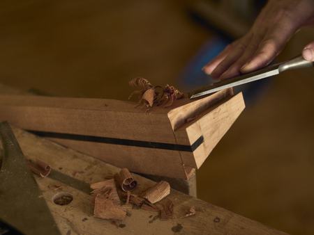 Luthier makes a neck block on a classical guitar.