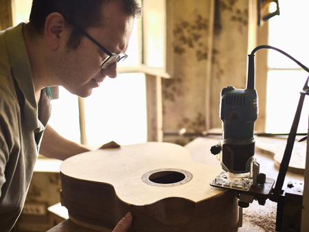 Luthier Install Binding on an guitar. Chamfering on the body of the guitar.の写真素材