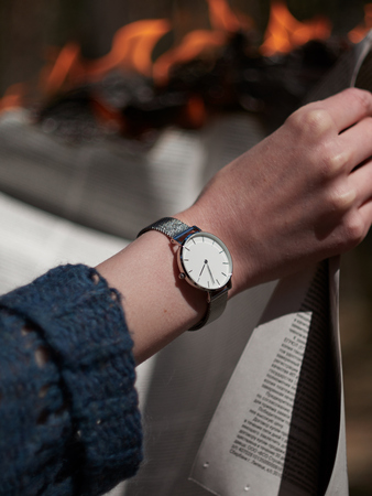 Female hand with a clock on the background of burning fire. Stylish photograph of a watch with a white dial.の写真素材