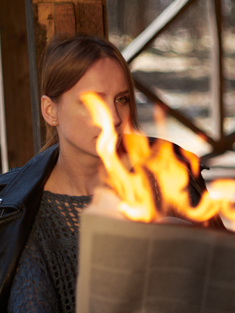 A young woman sits on the porch and reads hot news. A young woman sits on the porch and reads a burning newspaper.の写真素材