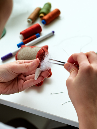 Step-by-step process of manual manufacturing baby crib mobile. stuff the toys with a sintepon.