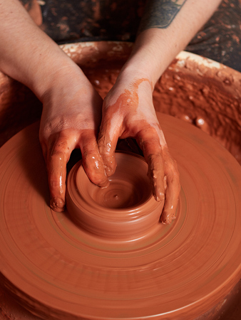 production process of pottery. Forming a clay teapot on a potter's wheel.
