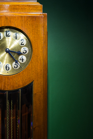 The dial of the outdoor clock is close-up on a green background.