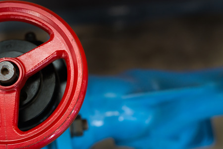 Gate valve with a red handgrip and a blue tube, close-up.