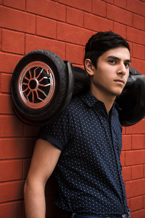 The guy holds a hoverboard behind his back.