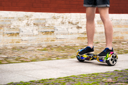 The guy in shorts is riding a color hoverboard. Legs close-up.