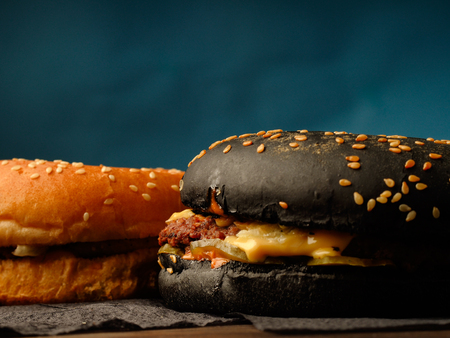Black and traditional hamburger on a wooden table on a blue background.の写真素材