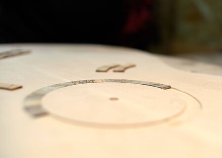 The guitar master pastes the rosette into a classical guitar.