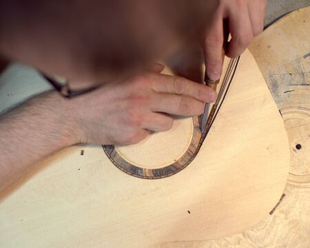 The guitar master installs  rosette in a classical guitar.