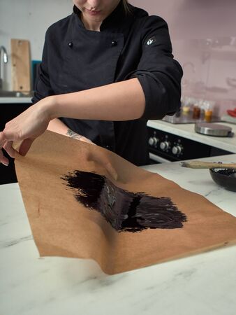 Step-by-step preparation of black designer cake. Preparation of chocolate glaze decorations for cake.の写真素材