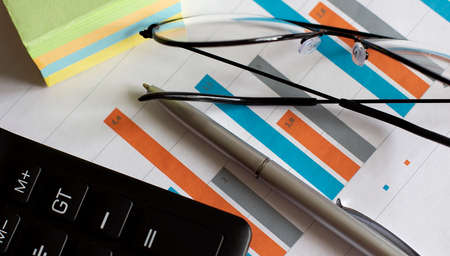 top view of business chart on white table with pen, calculator and glasses