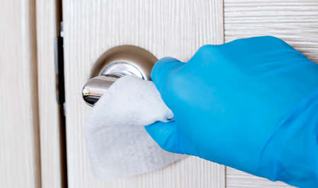 Actions to prevent the spread of coronavirus COVID-19, disinfection of the door handle. Hand in...