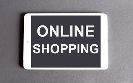 Online shopping concept - word on a digital tablet on gray background