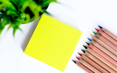 Colored pencils on a block yellow stickers on white backgroundの写真素材