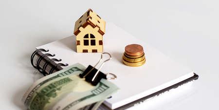 Mini wooden house and dollar banknote money on white background. Image for property real estate investment concept.の写真素材