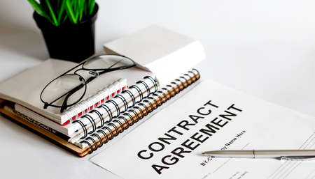 Close-up of silver pen on contract with notepads, glasses