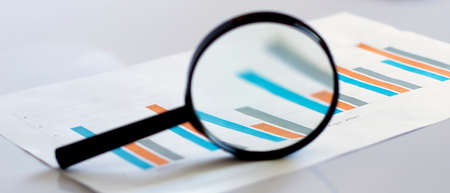 magnifying glass over financial newspaperの写真素材