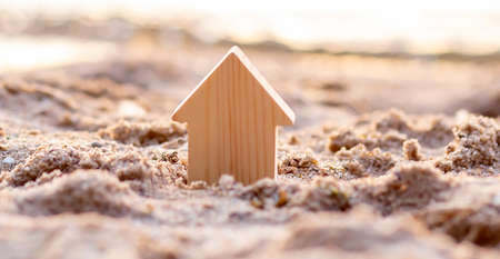 Small wooden house on sand background. Property conceptの写真素材