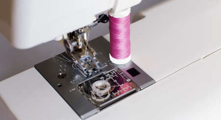 sewing machine and spool of tread on white background