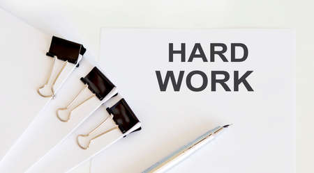 HARD WORK written on a white page with office toolsの写真素材
