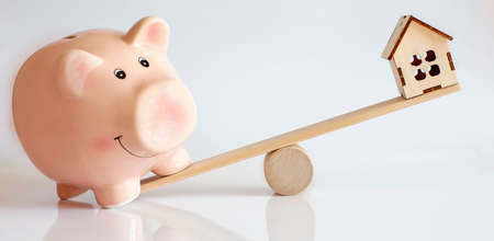 Balance between rose pig and wodden house. Concept save money on white backgroundの写真素材