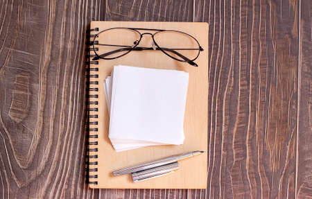notepad, pen, sticker and glasses. Writing tools. Office supplies. Isolated on wooden background