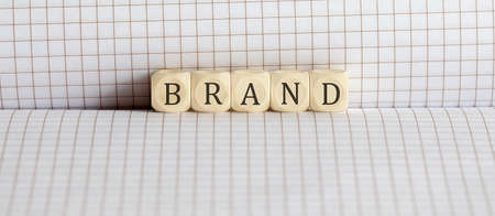 Concept BRAND. Words written on wooden block on notebook. Leadership concept.
