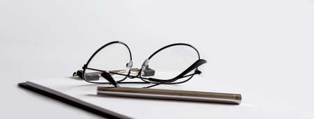 Glasses, pen on the paper on the white background