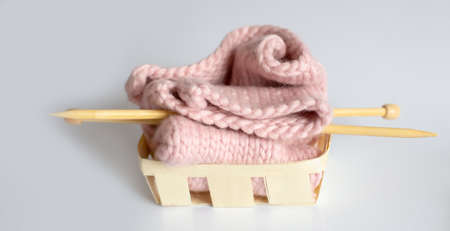 Knitting needles and pink yarn on the white background inthe basket