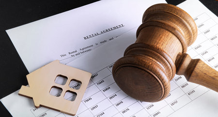 rental agreement form on desktop with pen, model wooden house, chart and gavel