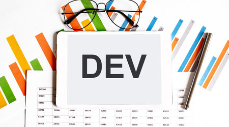 The tablet with text DEV on business charts and penの写真素材