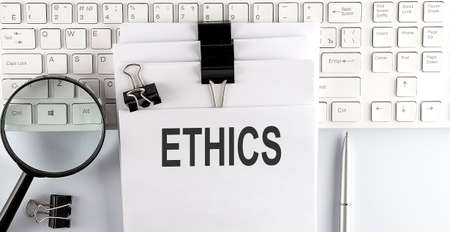 Words ETHICS written on papers on computer keyboard with magnifier and penの写真素材