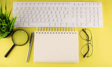 Office desk table Top view with keyboard, notebook copy space yellow backgroundの写真素材