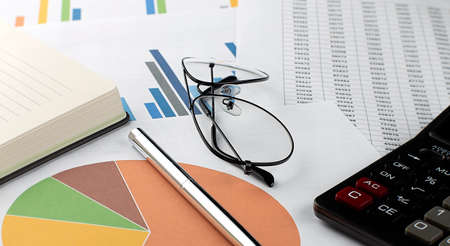 Chart, notepad, paper, calculator and pen on the tableの写真素材