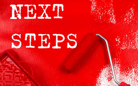 Roller brush with red paint with text NEXT STEPS, business