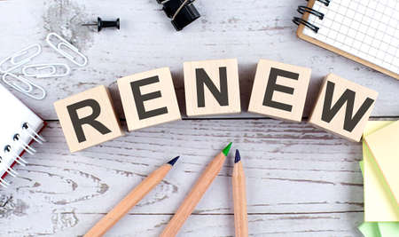 RENEW text on the wooden block with office tools on the wooden background