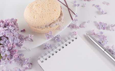 Home office: an open diary notebook with and lilac flowers on desk with tea and biscuitsの写真素材