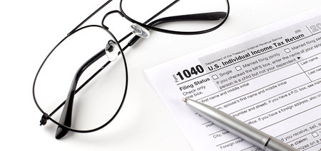 Blank income tax forms. American 1040 Individual Income Tax return form. With pen and glassesの写真素材